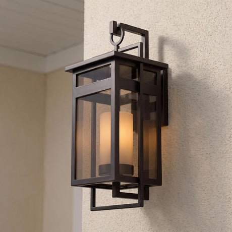 A modern home entry with the dark bronze Lansing Outdoor Wall Light and brown smoke glass glowing on a stucco wall at dusk under a white ceiling.