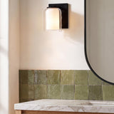 A contemporary bathroom featuring a matte black Orlando Vanity Wall Sconce 7" above green zellige tiles, a white marble countertop, and a black framed mirror.