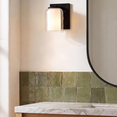 A contemporary bathroom featuring a matte black Orlando Vanity Wall Sconce 7" above green zellige tiles, a white marble countertop, and a black framed mirror.