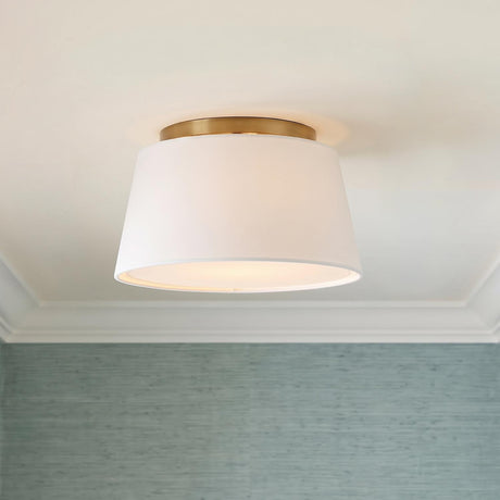 A transitional bedroom featuring the Barton Small Flush Mount 12 inch in aged brass and white linen above blue grasscloth wallpaper and white crown molding.