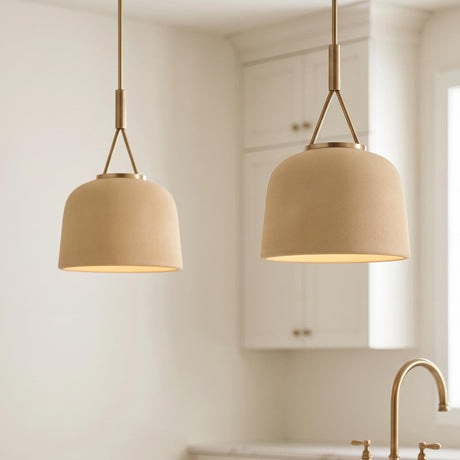 A transitional kitchen featuring two Stratford Small Pendant lights in Aged Brass and Terracotta hanging over an island near a brass faucet and white cabinets.