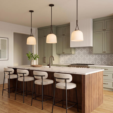 A transitional kitchen with three aged iron and opal glass pendants suspended over a white marble island featuring olive green cabinets and a patterned tile backsplash.