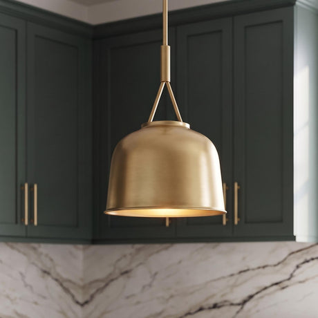 A transitional kitchen features an aged brass pendant light hanging in front of dark green shaker cabinets and a white marble backsplash.