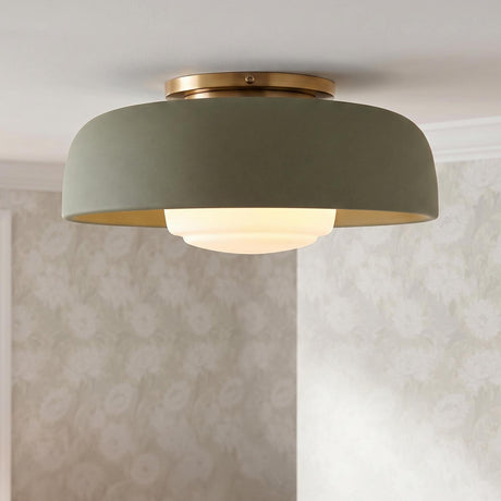 A transitional bedroom featuring the Stratford Medium Flush Mount in aged brass and thyme green mounted to a white ceiling beside neutral floral wallpaper.