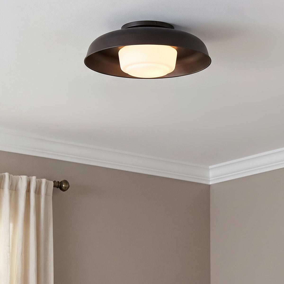 A transitional bedroom features a Stratford Medium Flush Mount 15 in aged iron and opal glass along the ceiling center with beige walls and crown molding.