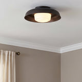 A transitional bedroom features a Stratford Medium Flush Mount 15 in aged iron and opal glass along the ceiling center with beige walls and crown molding.