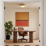 A mid-century office featuring the Stratford Medium Flush Mount in aged brass and beige centered above a walnut desk, tufted leather chair, and checkered flooring.