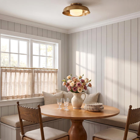 A modern farmhouse dining nook featuring the Stratford Medium Flush Mount in aged brass and opal glass installed over a round oak pedestal table and shiplap walls.