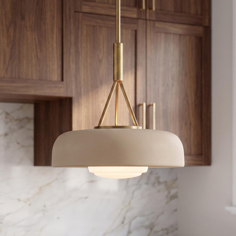A contemporary kitchen with a Stratford Medium Pendant featuring an aged brass finish and beige shade hanging over a white marble backsplash and dark walnut cabinets.