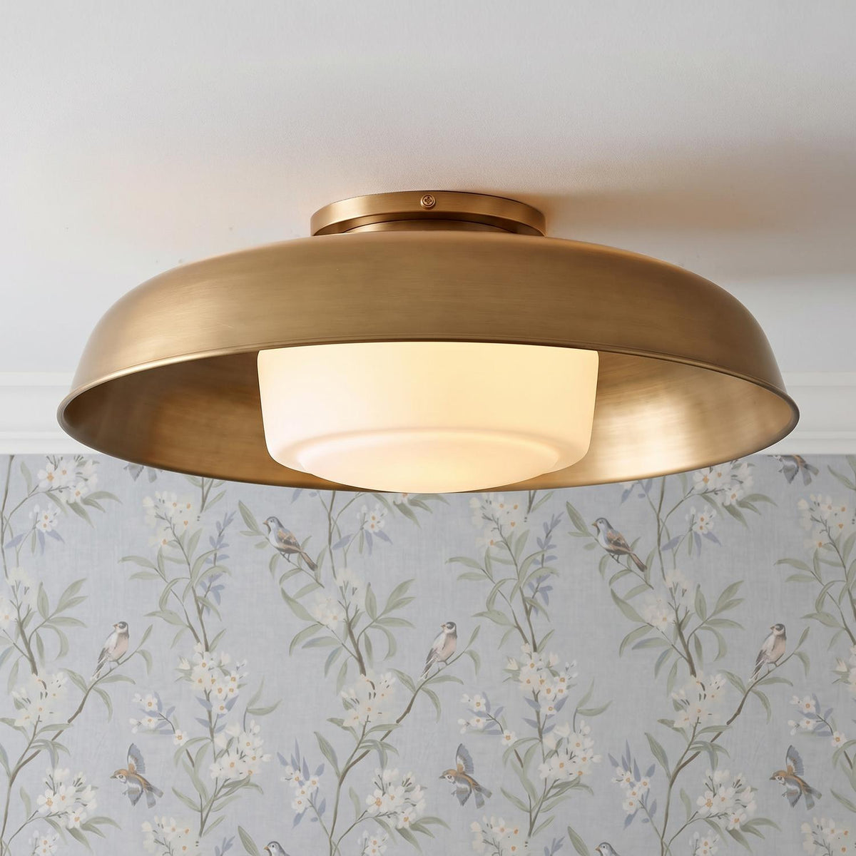 A traditional foyer with the Stratford Large Flush Mount 20", Aged Brass and Opal Glass installed along the ceiling above light blue floral bird wallpaper.