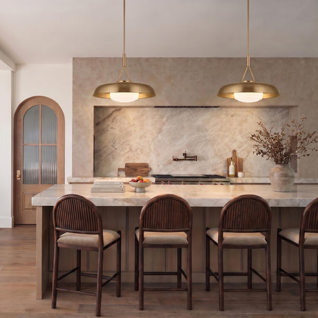 A transitional kitchen featuring two Stratford Large Pendants in aged brass suspended over a white marble island with dark wood bar stools and a stone backsplash.