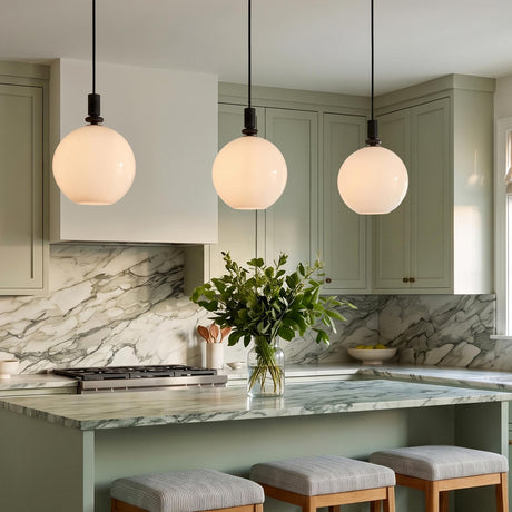A transitional kitchen with three Filomena Medium Pendant 14" matte black and milk glass globes over a sage green marble-topped island and matching shaker cabinets.