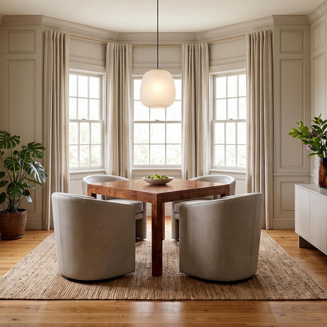 A transitional dining room with a frosted glass pendant with satin brass hardware hanging over a wood burl table and gray swivel chairs in a bay window.