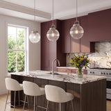 A transitional kitchen features three Whitaker Pendant 10" lights in brushed nickel and clear ribbed glass hanging over a marble-topped island with plum cabinetry.