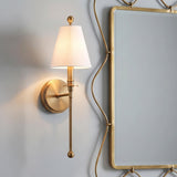A transitional bathroom featuring the Bellamy Wall Sconce 20" in aged brass with a white fabric shade installed on grey walls beside a gold-framed scalloped mirror.
