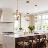 A traditional kitchen features three Alice Lantern Pendant 11", Antique Gold fixtures hanging over a white marble waterfall island with dark wood bar stools and white cabinetry.