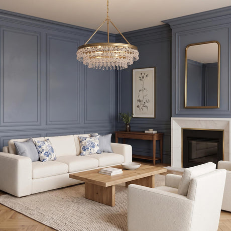 A traditional living room with the Betony 6 Light Chandelier in Aged Brass hanging above a wood coffee table, featuring blue paneled walls and a white marble fireplace.