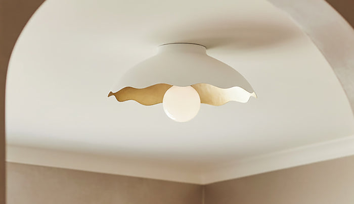 Poset Flush Mount Ceiling light has a ruffled edge and brass interior for a trendy and modern look.