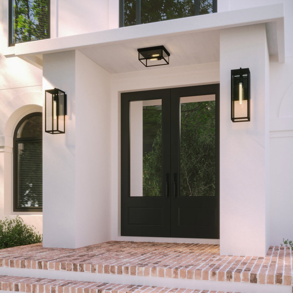Sam Large 24" Wall Lights and 12" Flush Mount Ceiling Light are shown together on a white stucco home with black front doors and a brick porch. 